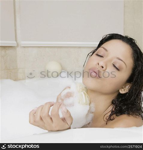 Side profile of a teenage girl scrubbing her body in the bathtub