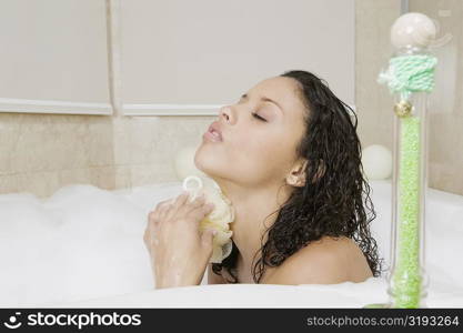 Side profile of a teenage girl scrubbing her body in the bathtub