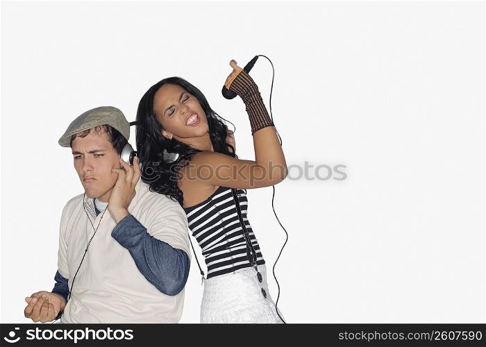 Side profile of a teenage girl singing and a young man listening to music