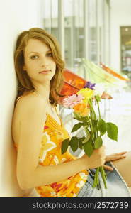 Side profile of a teenage girl sitting and holding a bouquet of flowers