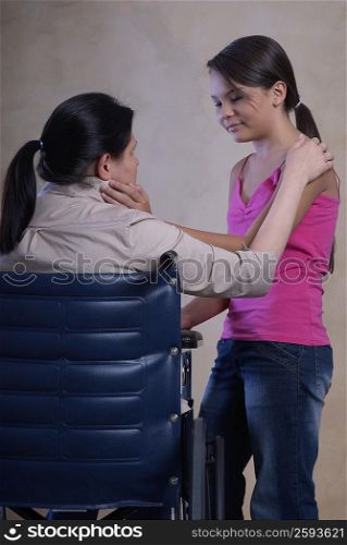 Side profile of a teenage girl standing beside her mother in a wheelchair