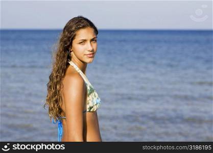 Side profile of a teenage girl standing on the beach