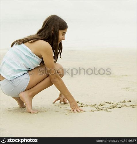 Side profile of a teenage girl writing in sand
