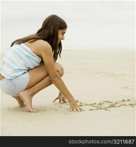 Side profile of a teenage girl writing in sand