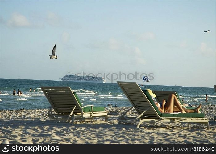 Side profile of a woman reclining on a lounge chair on the beach
