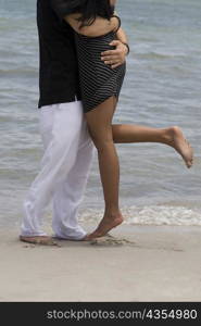 Side profile of a young couple embracing each other on the beach