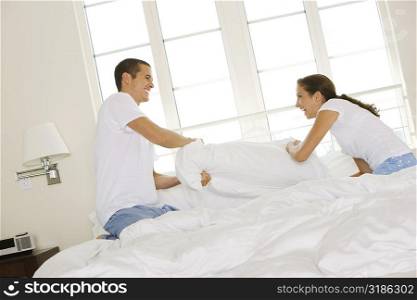 Side profile of a young couple having a pillow fight