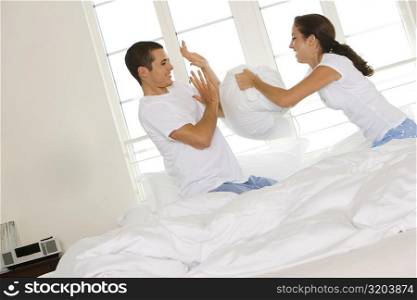 Side profile of a young couple having a pillow fight