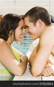 Side profile of a young couple looking at each other at the poolside