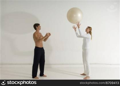 Side profile of a young couple playing with a fitness ball