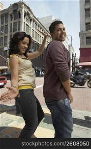 Side profile of a young couple reggaeton dancing on the road