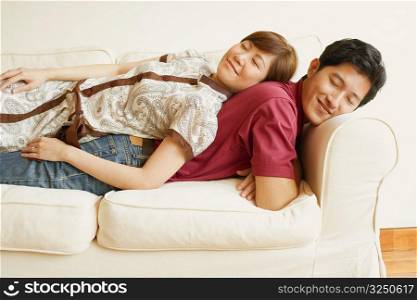 Side profile of a young couple sleeping back to back on a couch