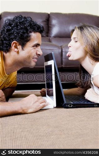 Side profile of a young couple using laptops