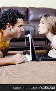 Side profile of a young couple using laptops