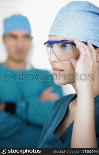Side profile of a young female doctor holding his protective eyewear