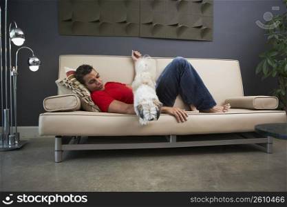 Side profile of a young man and a dog lying on a couch