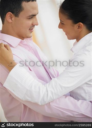 Side profile of a young man and a teenage girl looking at each other and smiling