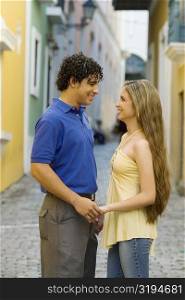 Side profile of a young man and a teenage girl standing face to face on the street