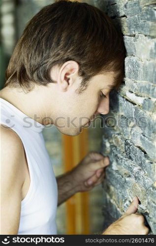 Side profile of a young man banging his head against a wall