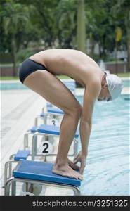Side profile of a young man bending on a starting block