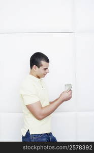 Side profile of a young man counting dollar bills