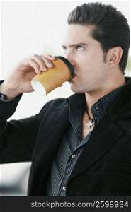 Side profile of a young man drinking coffee