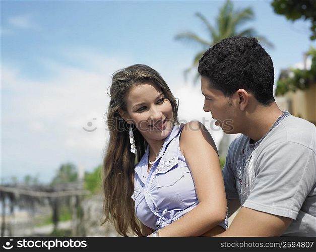 Side profile of a young man embracing a young woman from behind
