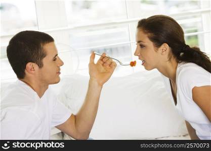 Side profile of a young man feeding a young woman cherries