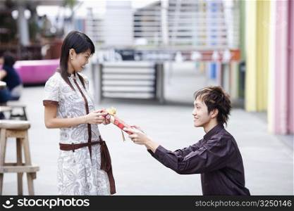 Side profile of a young man giving a gift to a young woman
