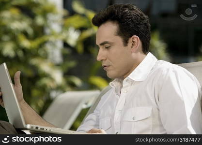 Side profile of a young man holding a laptop