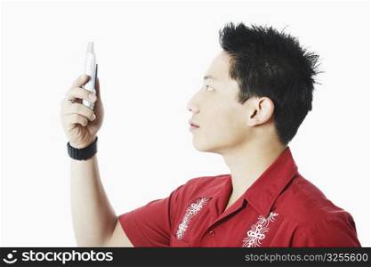 Side profile of a young man holding a mobile phone