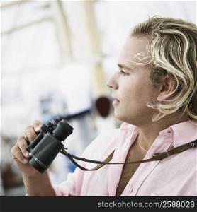 Side profile of a young man holding a pair of binoculars