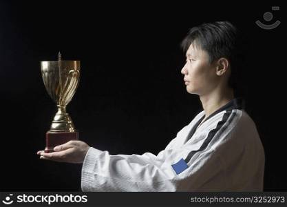 Side profile of a young man holding a trophy
