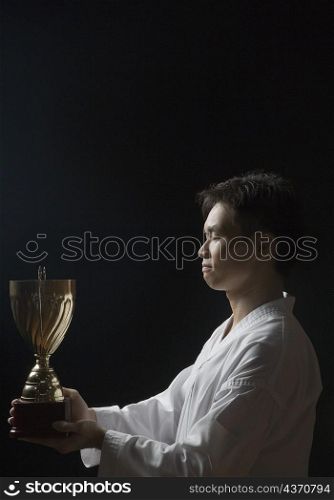 Side profile of a young man holding a trophy