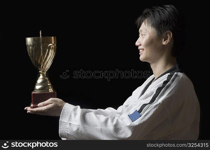 Side profile of a young man holding a trophy and smiling