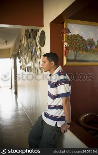 Side profile of a young man leaning against a wall and thinking
