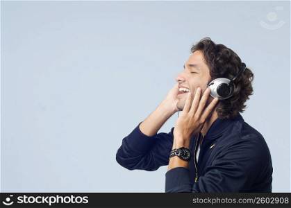 Side profile of a young man listening to music and smiling