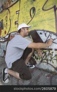 Side profile of a young man making a graffiti on a wall