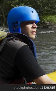 Side profile of a young man rafting in a river