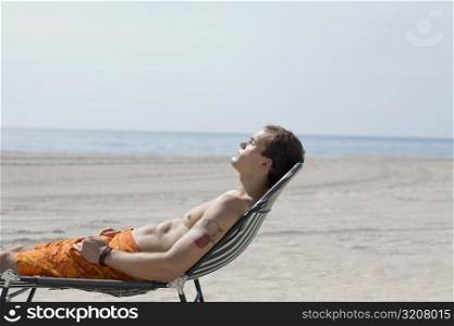 Side profile of a young man relaxing on the beach