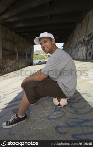 Side profile of a young man sitting on a soccer ball