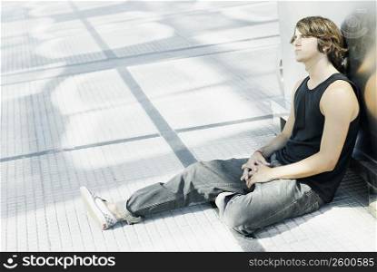 Side profile of a young man sitting on the floor