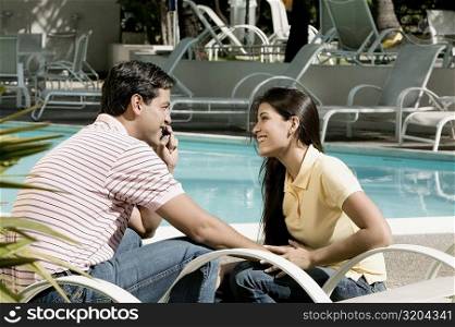 Side profile of a young man talking on a mobile phone with a young woman sitting in front of him