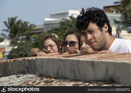 Side profile of a young man with three young women looking over a castle wall, Morro Castle, Old San Juan, San Juan, Puerto Rico