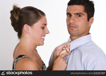 Side profile of a young woman adjusting a mid adult man&acute;s tie