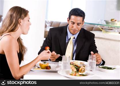 Side profile of a young woman and a mid adult man eating in a restaurant