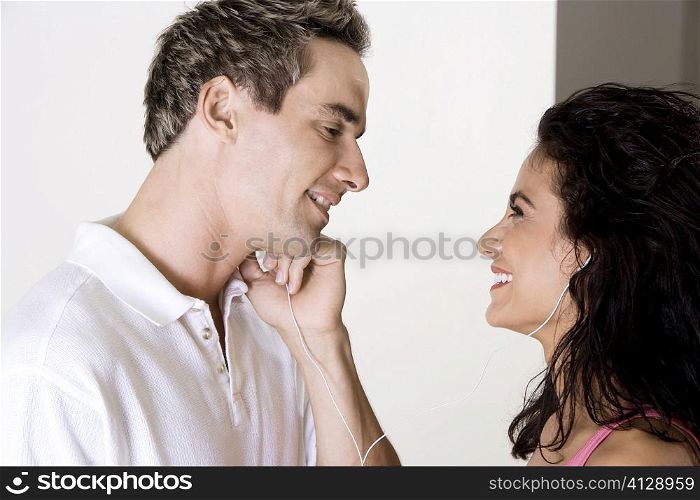 Side profile of a young woman and a mid adult man listening to music through earphones