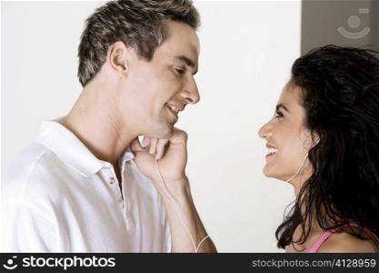 Side profile of a young woman and a mid adult man listening to music through earphones
