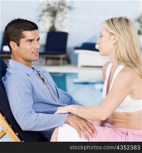 Side profile of a young woman and a mid adult man sitting on a deck chair
