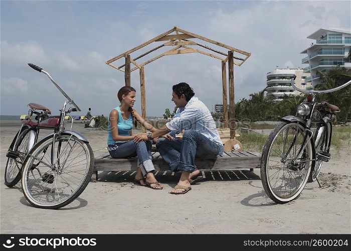 Side profile of a young woman and a mid adult man sitting beside their bicycles